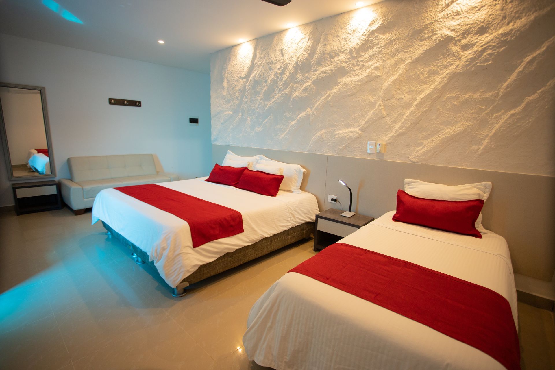 Habitaciones en coveñas del Hotel Poblado con cama matrimonial y cama sencilla, y sábanas rojas y blancas