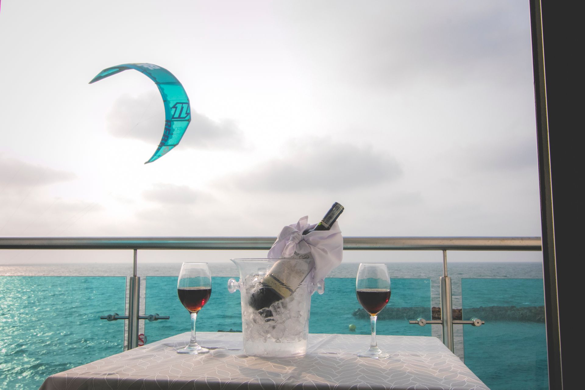 Chilled wine bottle and glasses on a balcony overlooking the sea and a kitesurfer at Hotel Poblado Coveñas