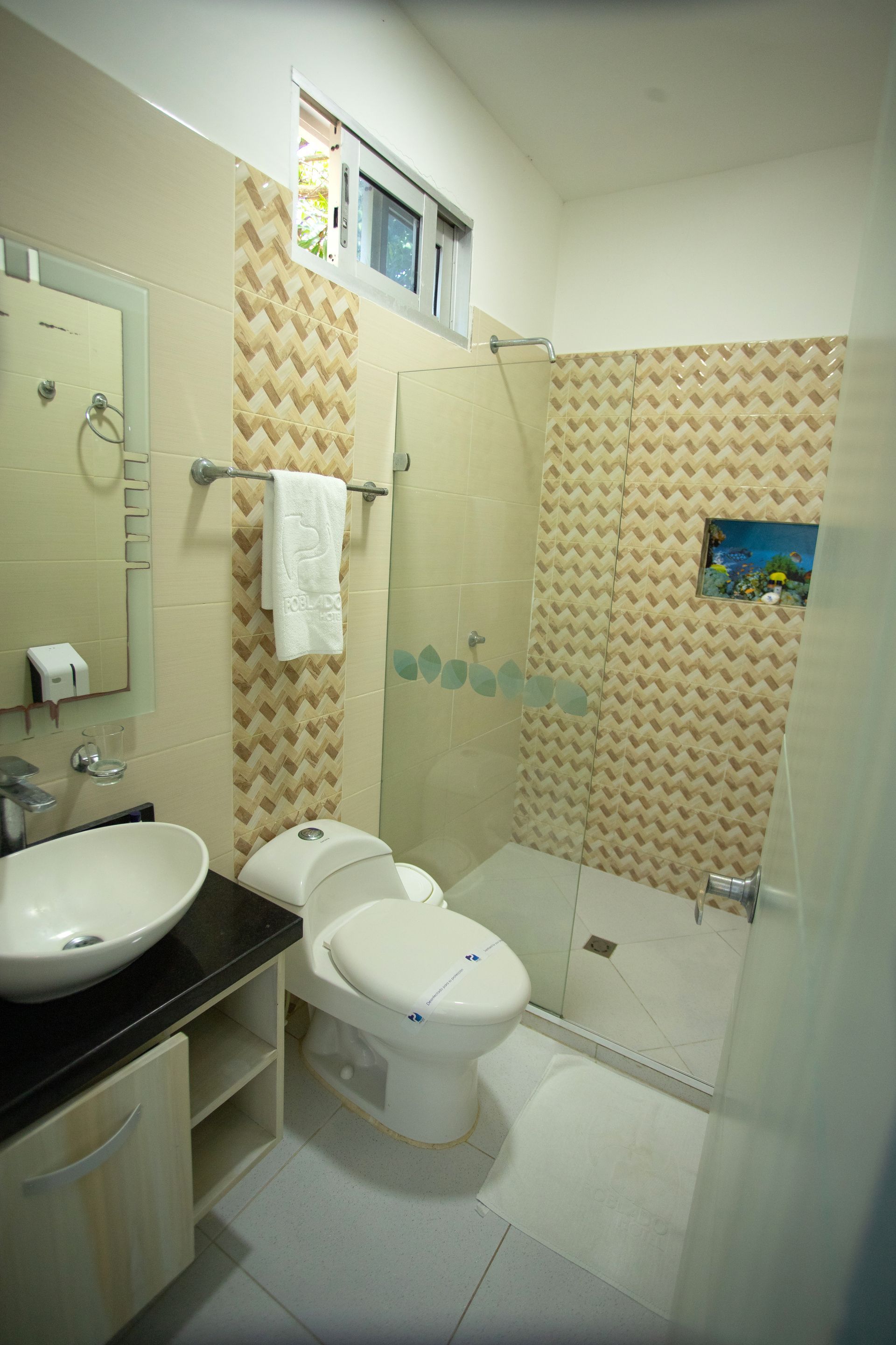 Clean hotel bathroom with tiled shower and window for your comfortable stay at a beach hotel in Coveñas