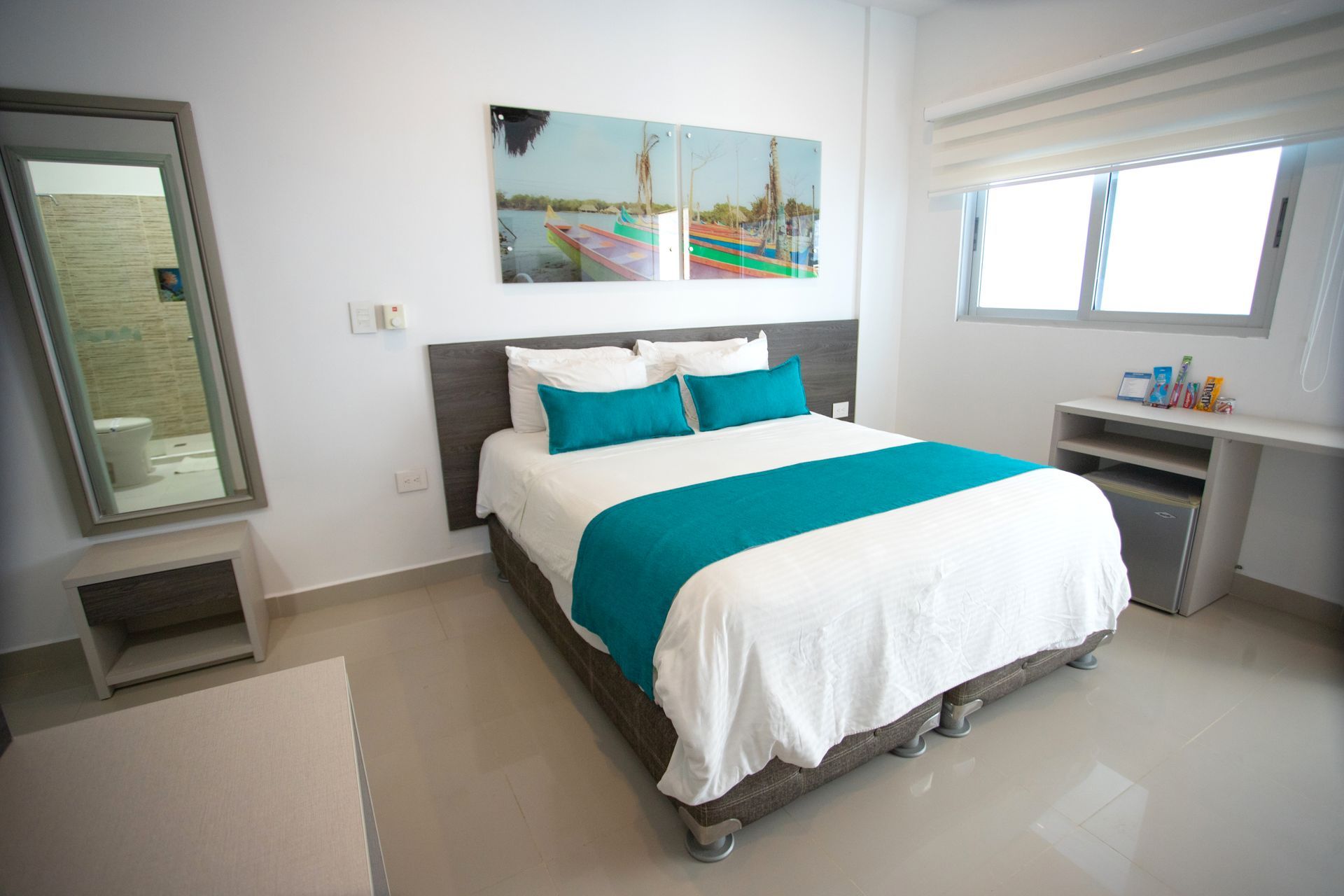 habitaciones en coveñas en Hotel Poblado con cama matrimonial, espejo de cuerpo entero, cuadro y mesa auxiliar