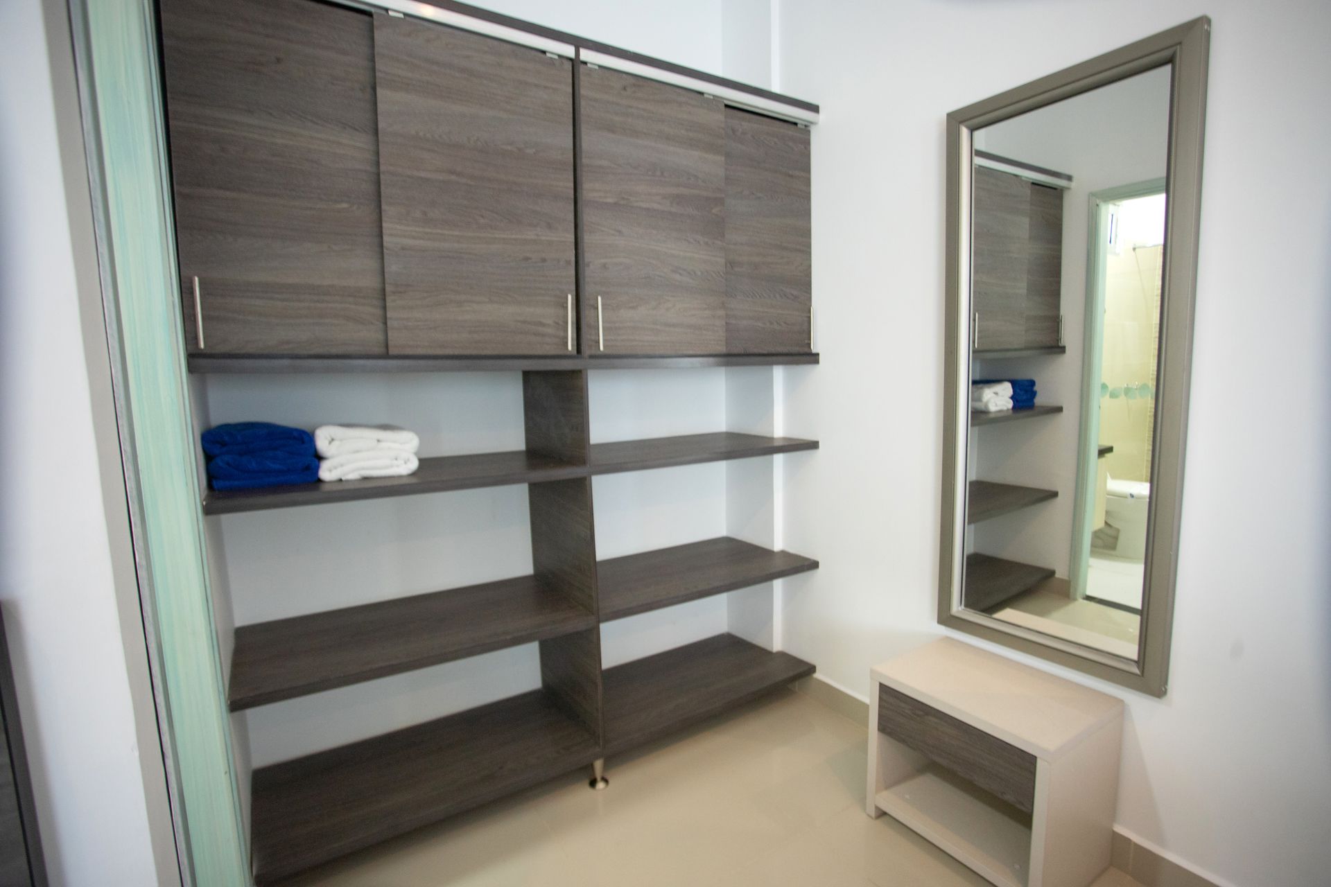 Hotel room dressing area with wooden shelving and large mirror for your stay at a top beach hotel in Coveñas