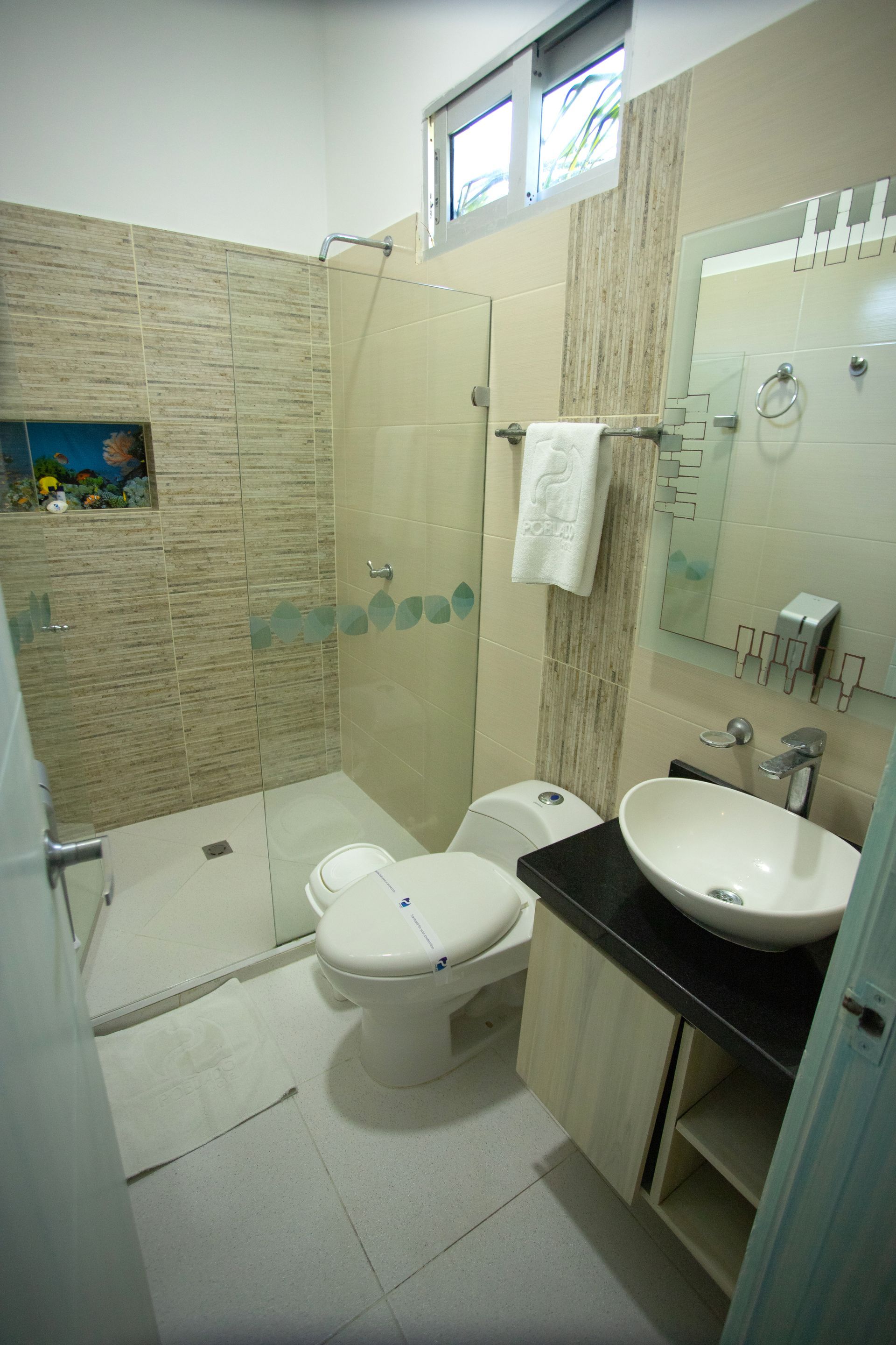 hotel bathroom with tiled shower and glass partition for your relaxing vacation at a beach hotel in Coveñas
