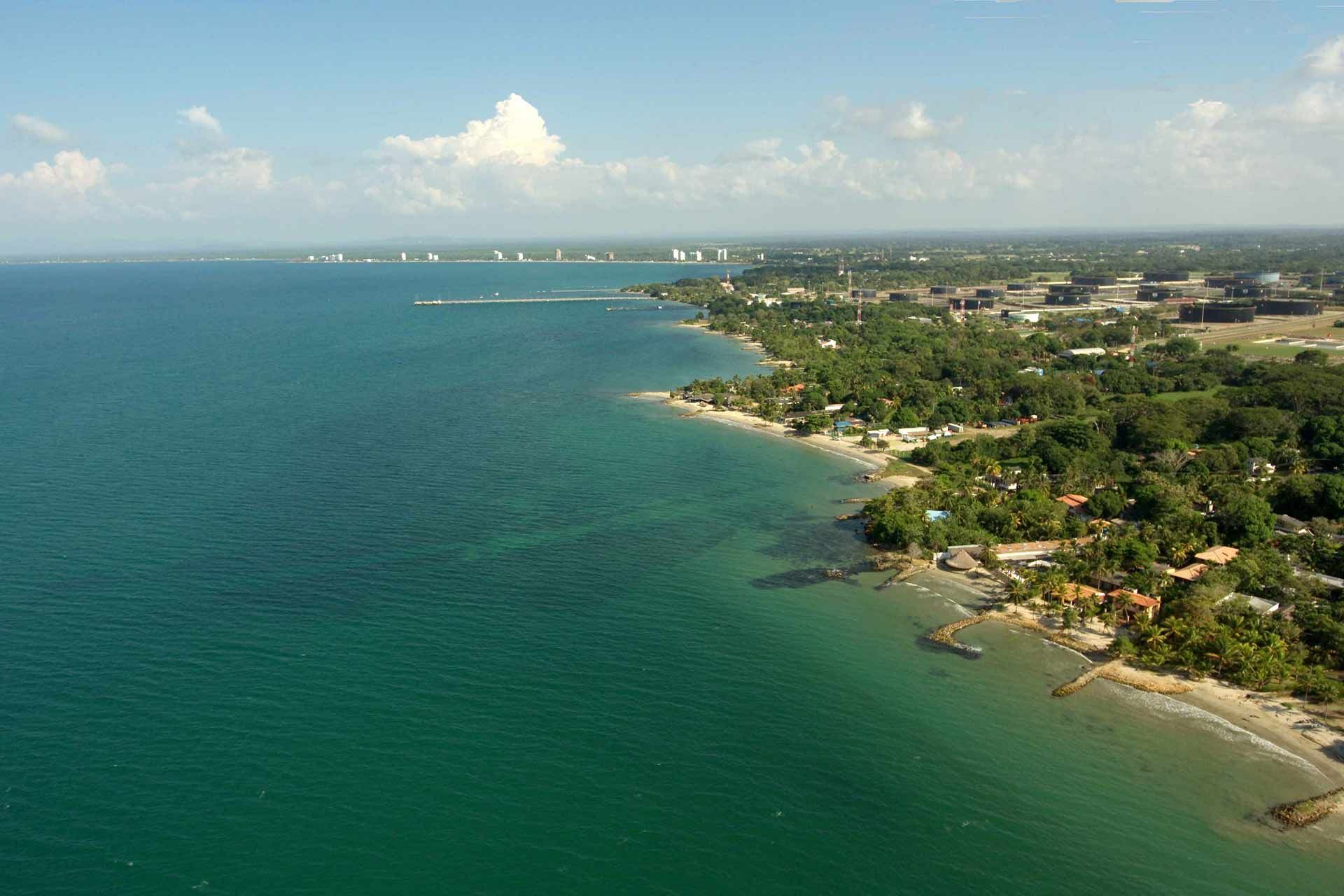 Aerial panoramic view of dense coastal vegetation beside turquoise sea, ideal for tours in Coveñas Colombia