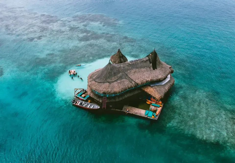 Eco lodge with thatched roofs built over turquoise water in San Bernardo Islands near Hotel Poblado Coveñas