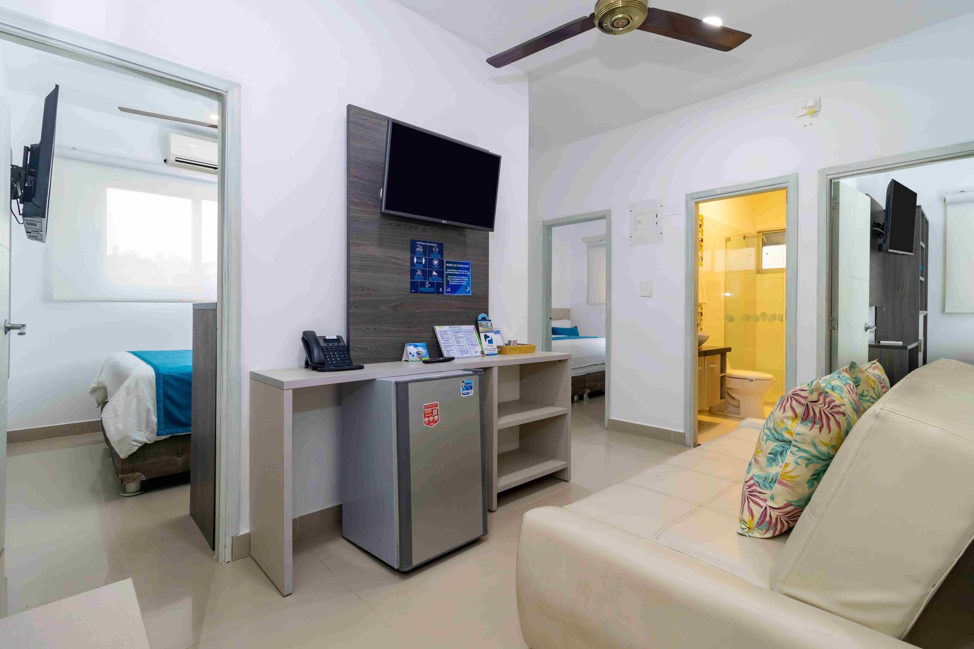 habitaciones en coveñas, con varias camas, televisor, mini venera y baño en Hotel Poblado