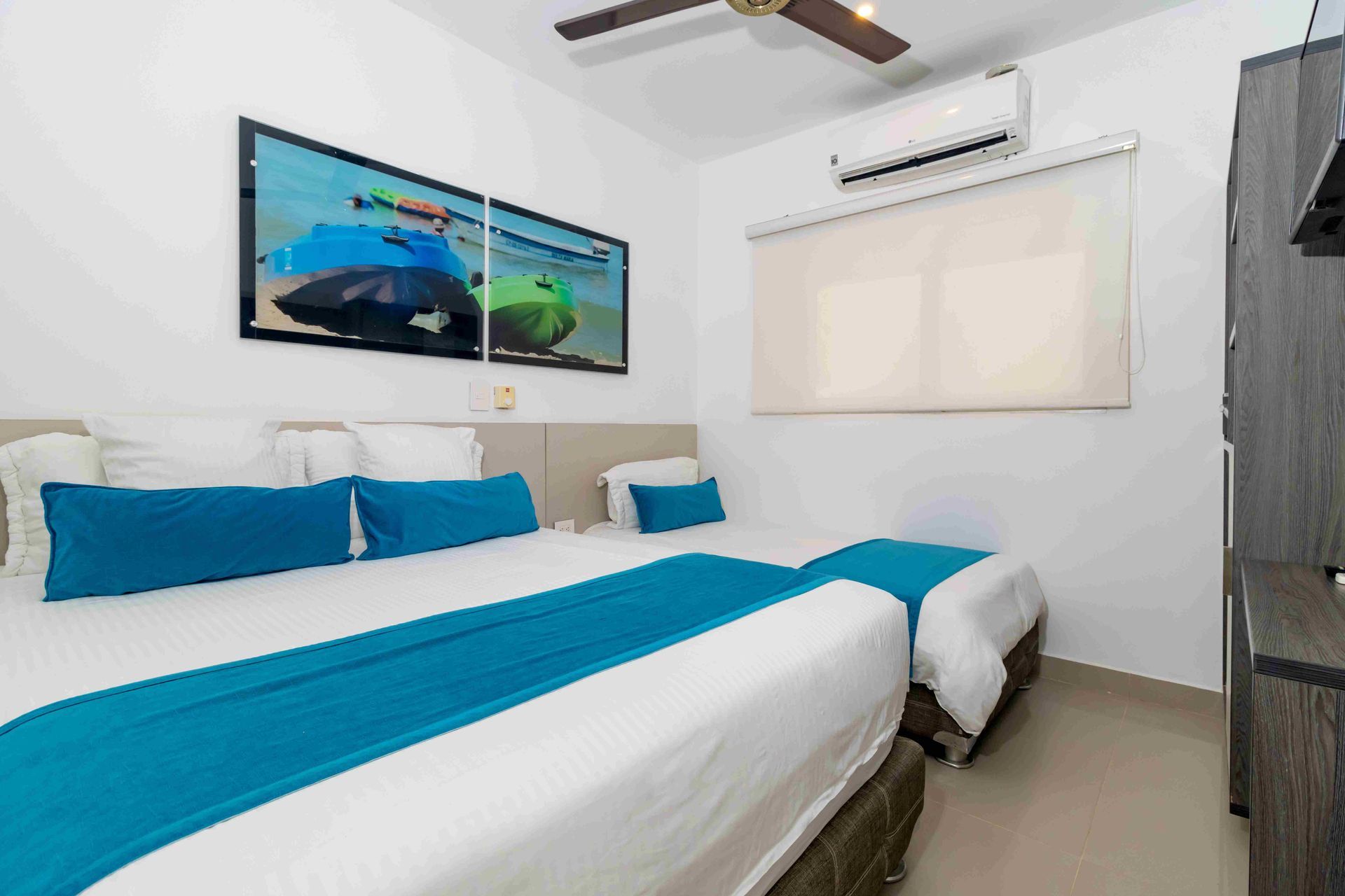 habitaciones en coveñas del Hotel Poblado con camas múltiples, cuadro, ventilador y aire acondicionado
