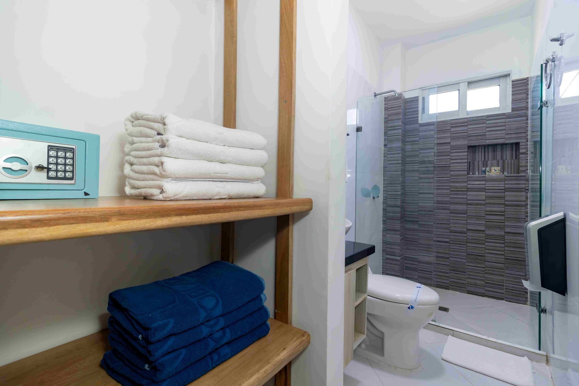 Baño con ducha y estantería de madera con toallas en Hotel Poblado Coveñas