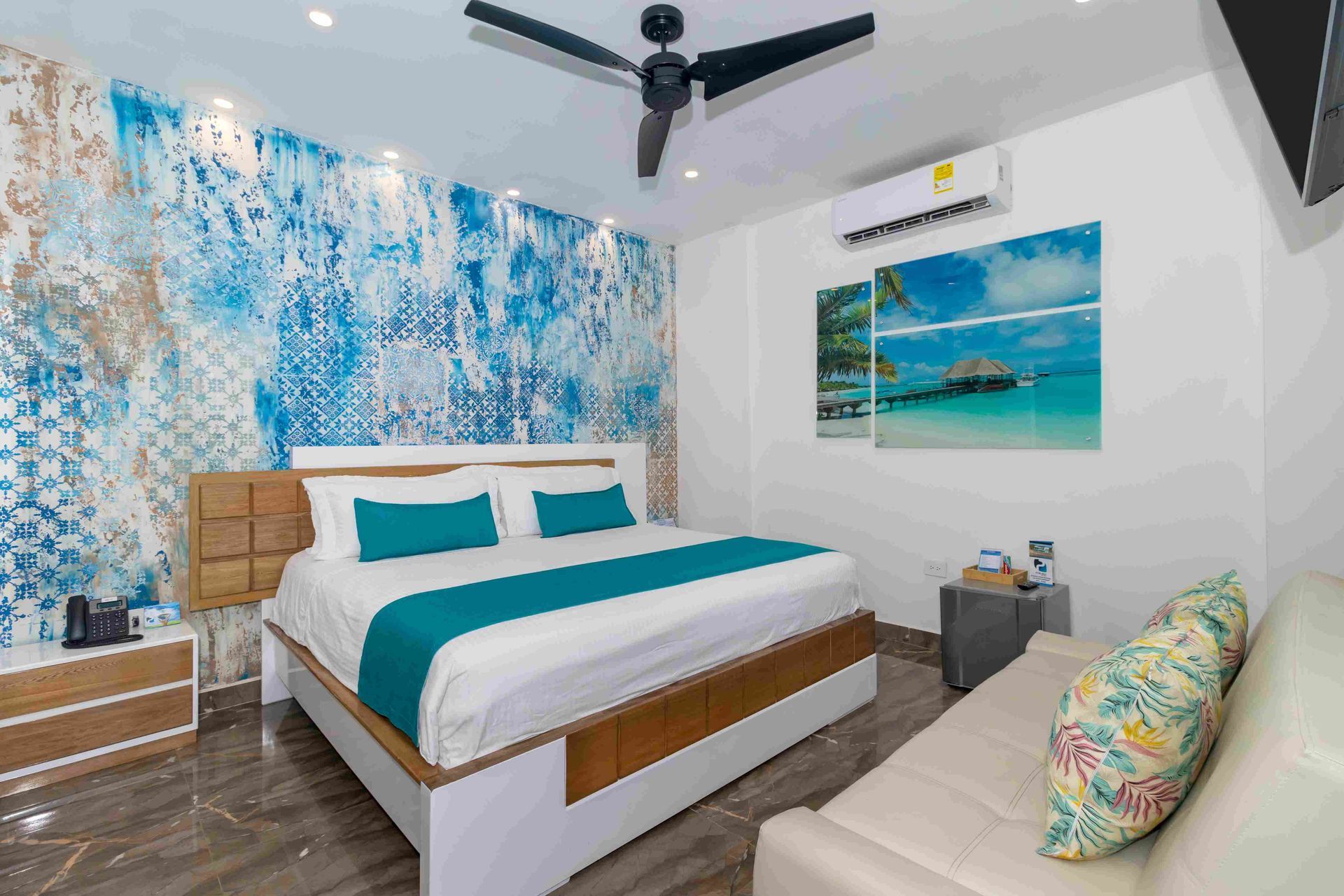 habitaciones en coveñas en Hotel Poblado, con cama matrimonial, sábanas azules, sofá y aire acondicionado