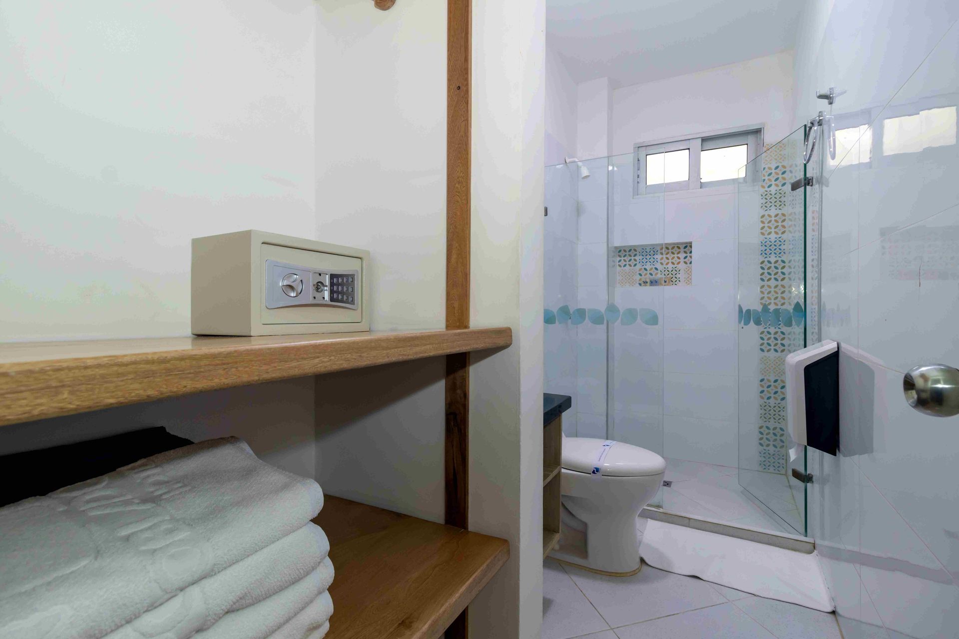 Estantería con caja fuerte y baño moderno en habitaciones en coveñas del Hotel Poblado