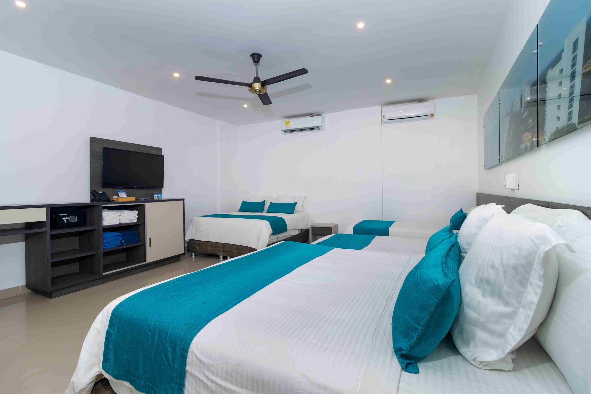 habitaciones en Coveñas del Hotel Poblado con camas múltiples, televisor, aire acondicionado y ventilador en el techo