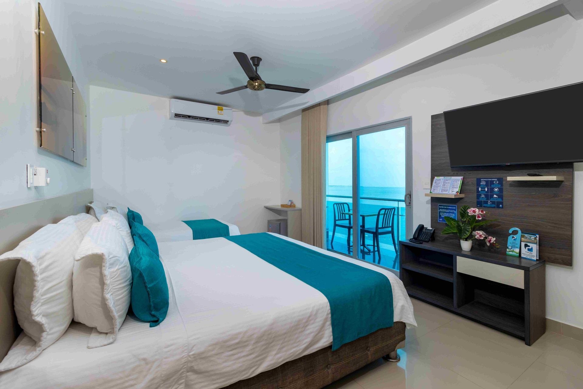 habitaciones en coveñas en Hotel Poblado con cama matrimonial, televisor, ventilador y vista al mar
