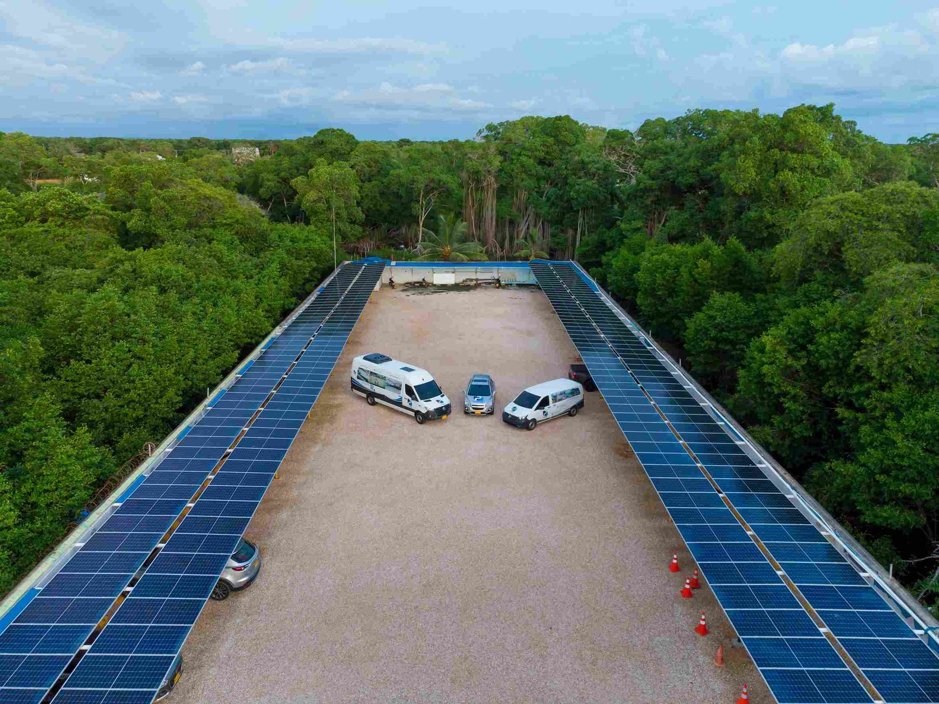 hotel con parqueadero con carros estacionados, bajo paneles solares, ideal para un hospedaje en Hotel Poblado