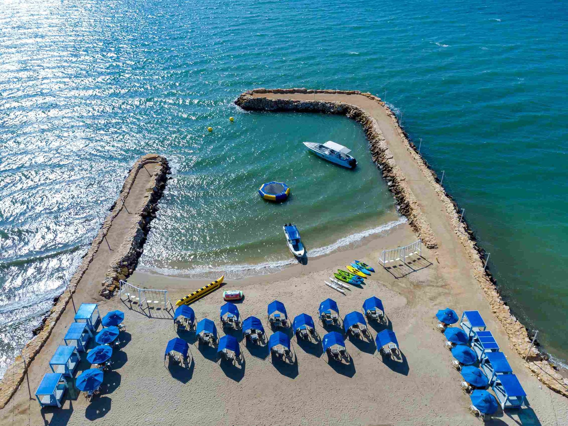 Muelle del Hotel Poblado Coveñas, con carpas azules y embarcaciones, uno de los hoteles en coveñas cerca al mar.