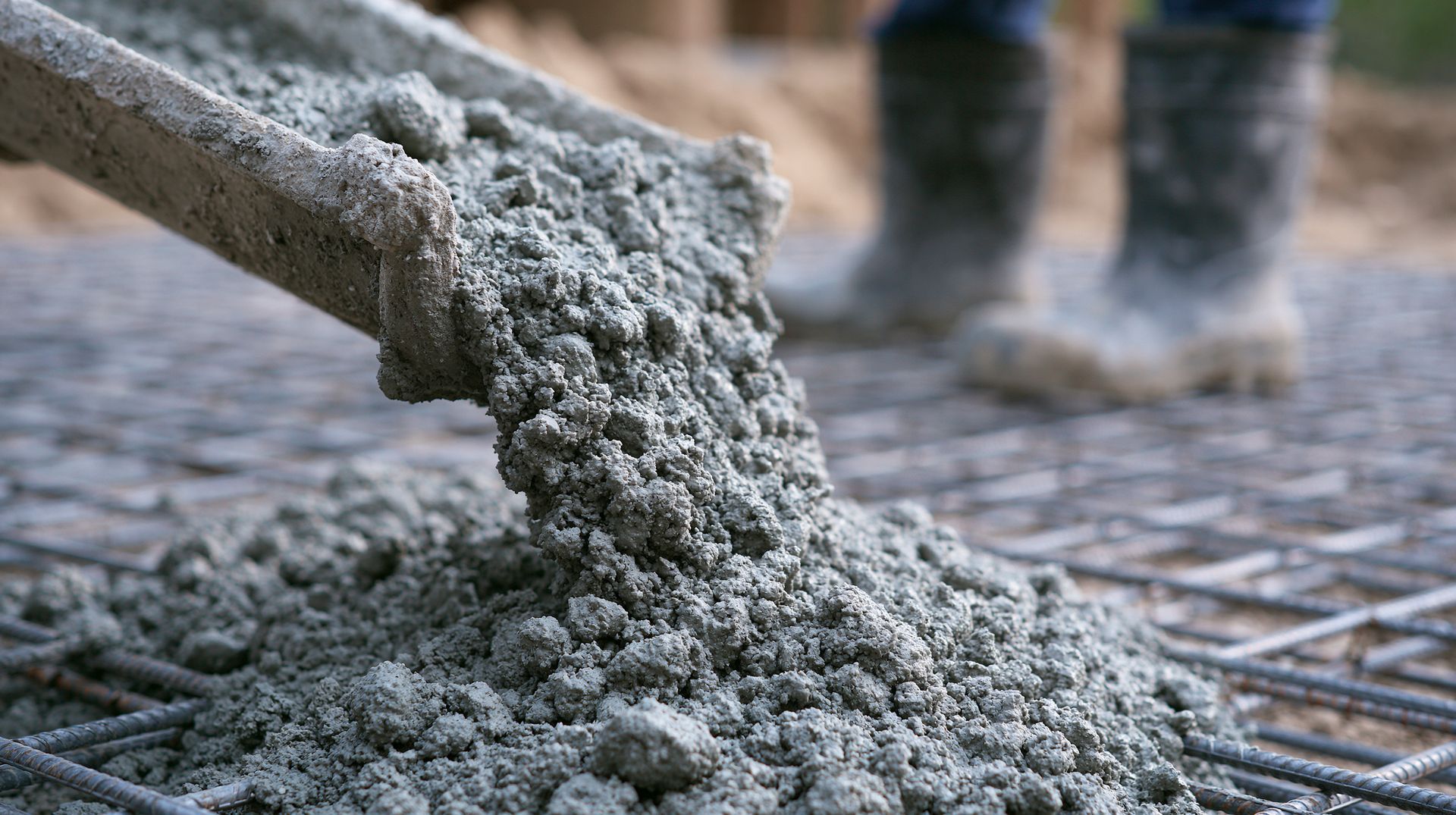 Fresh concrete pouring from the chute onto steel rebar as concrete ready-mix suppliers fill a slab. Fresh concrete pouring from the chute onto steel rebar as concrete ready-mix suppliers fill a slab.