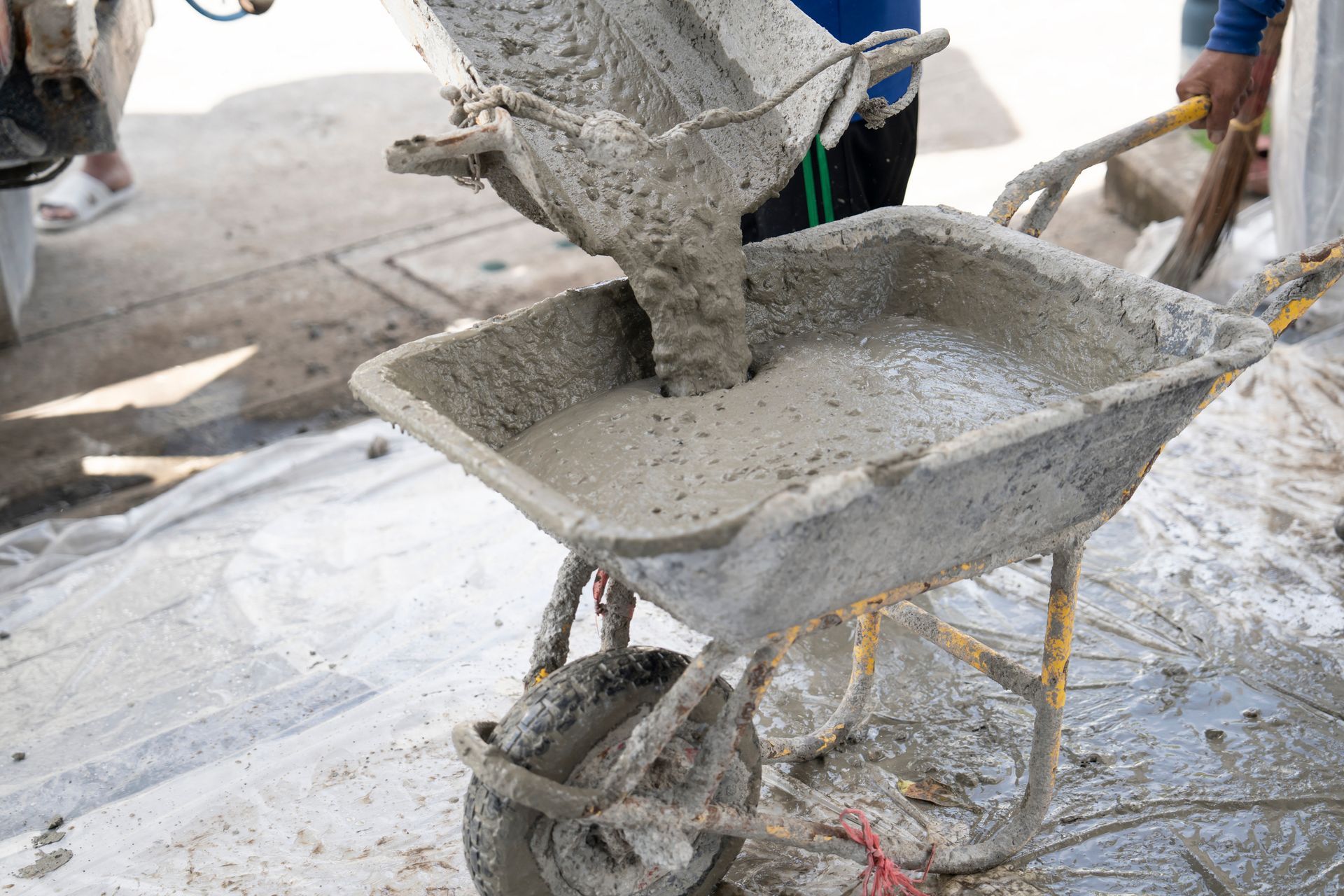 Fresh wet concrete being poured into a wheelbarrow for construction work.