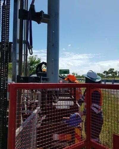 A Man In A Hard Hat Is Standing In Front Of A Red Fence — PGI North QLD In Mount Isa, QLD