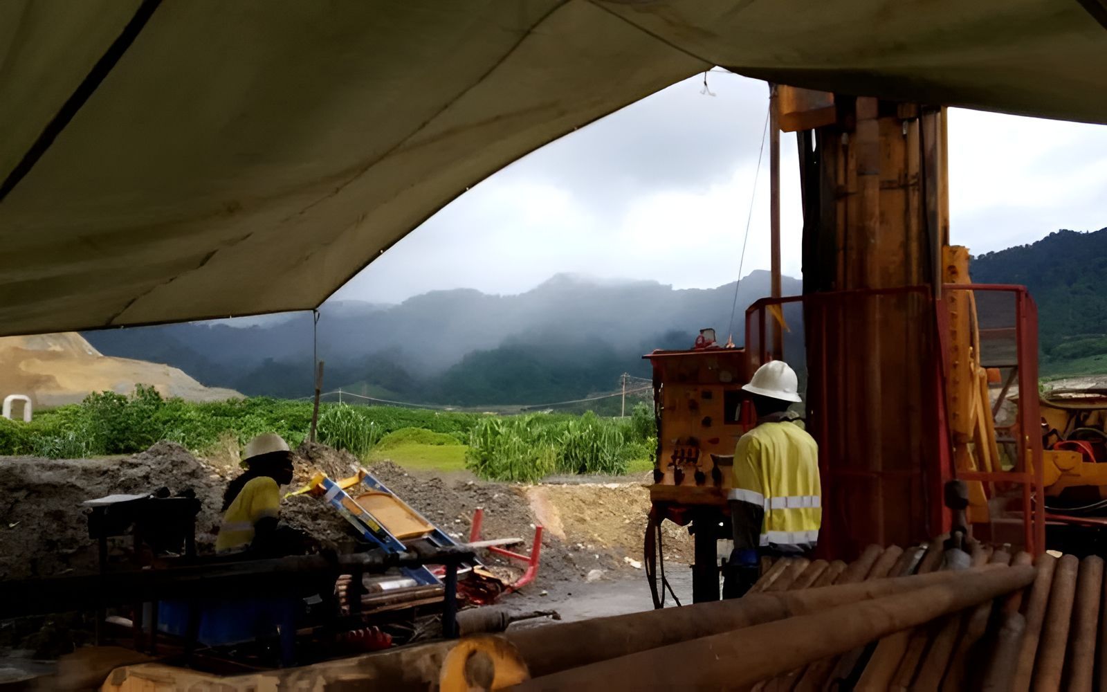 A Man Is Working On A Machine In A Field With Mountains — PGI North QLD In Burketown, QLD