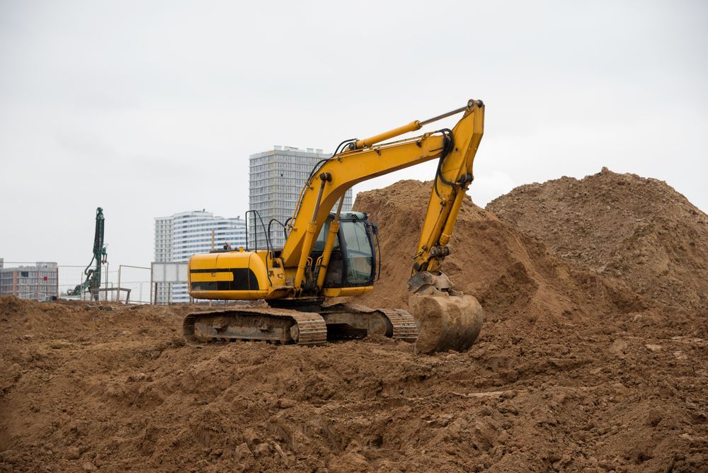 A Yellow Excavator Is Digging A Pile Of Dirt On A Construction Site — PGI North QLD In Rosslea, QLD