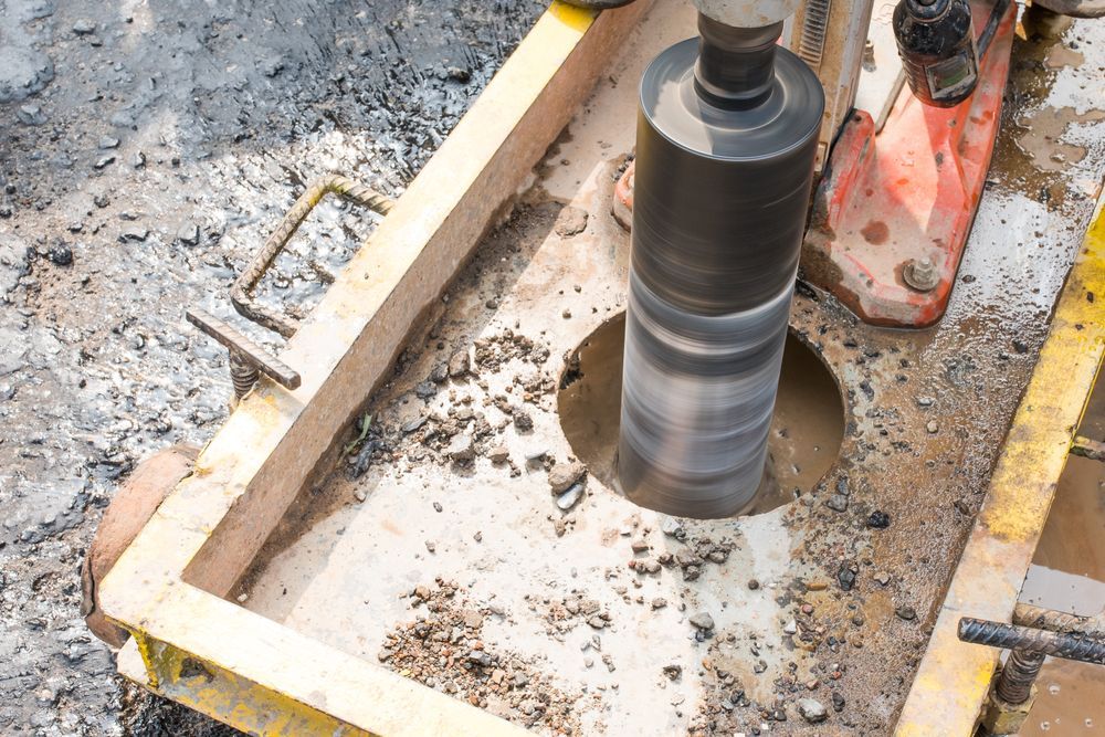 A Person Is Using A Machine To Drill A Hole In The Ground — PGI North QLD In Ayr, QLD