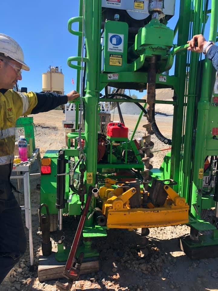 A Man Is Working On A Green And Yellow Drilling Machine — PGI North QLD In Ingham, QLD
