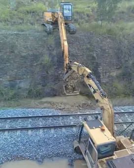 A Yellow Excavator Is Working On A Train Track — PGI North QLD In Mount Isa, QLD