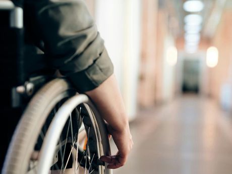 A person in a wheelchair is standing in a hallway.
