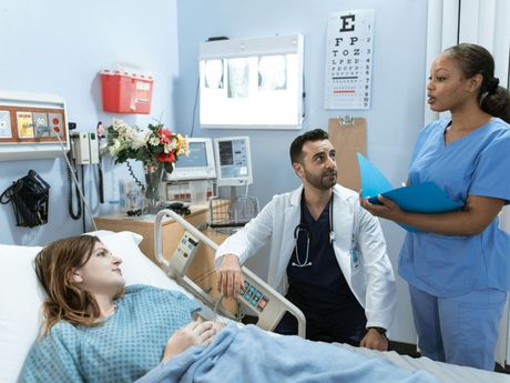 A doctor and nurse are talking to a patient in a hospital bed.