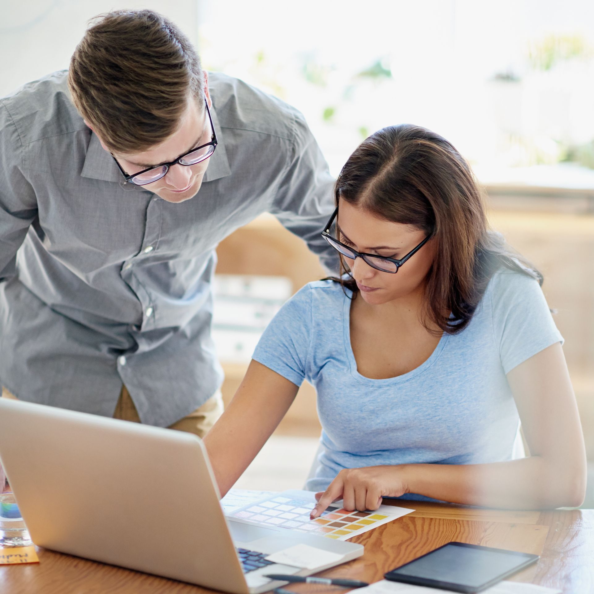 A man and a woman are looking at a laptop together