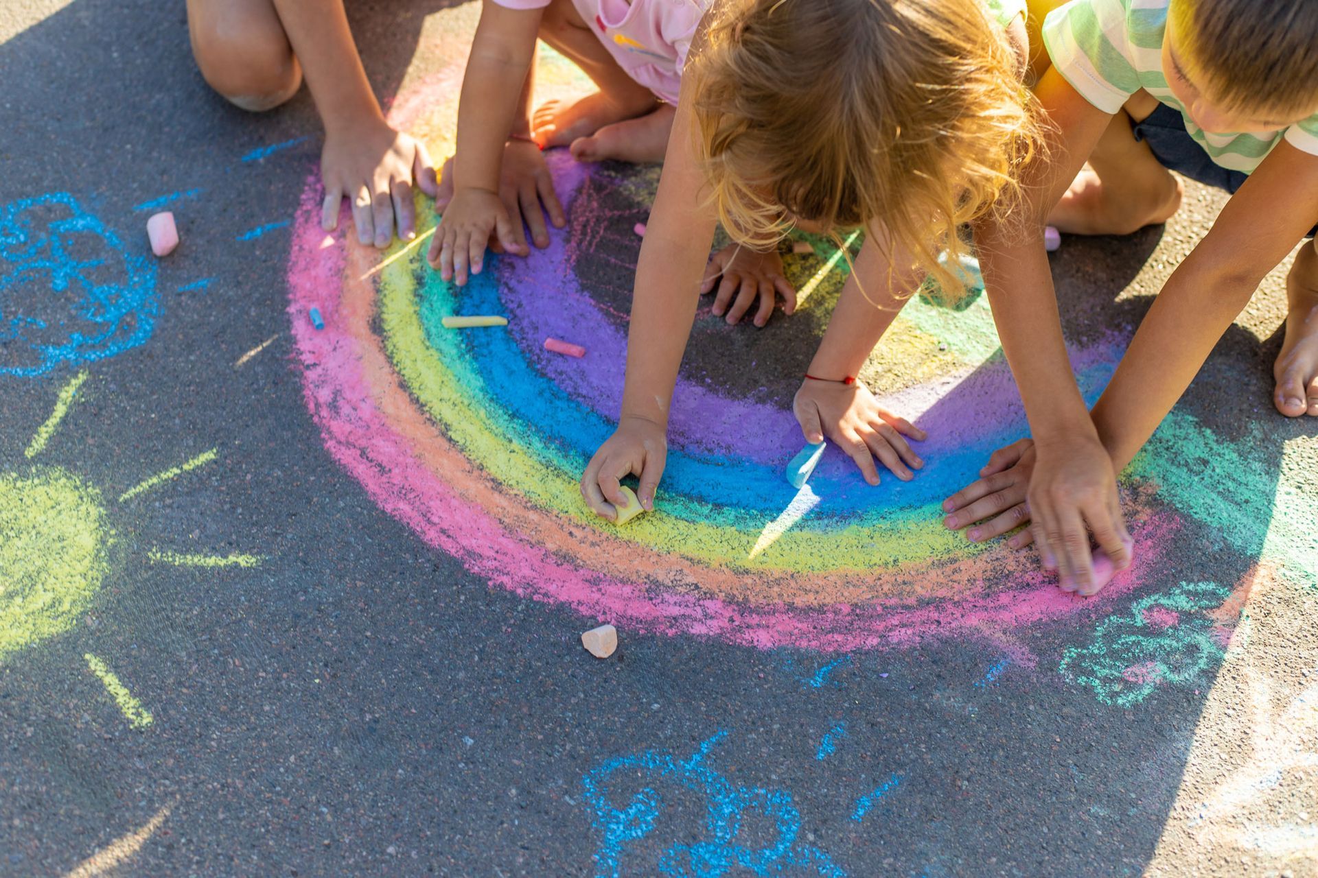 Young kids colouring with chalk on sidewalk