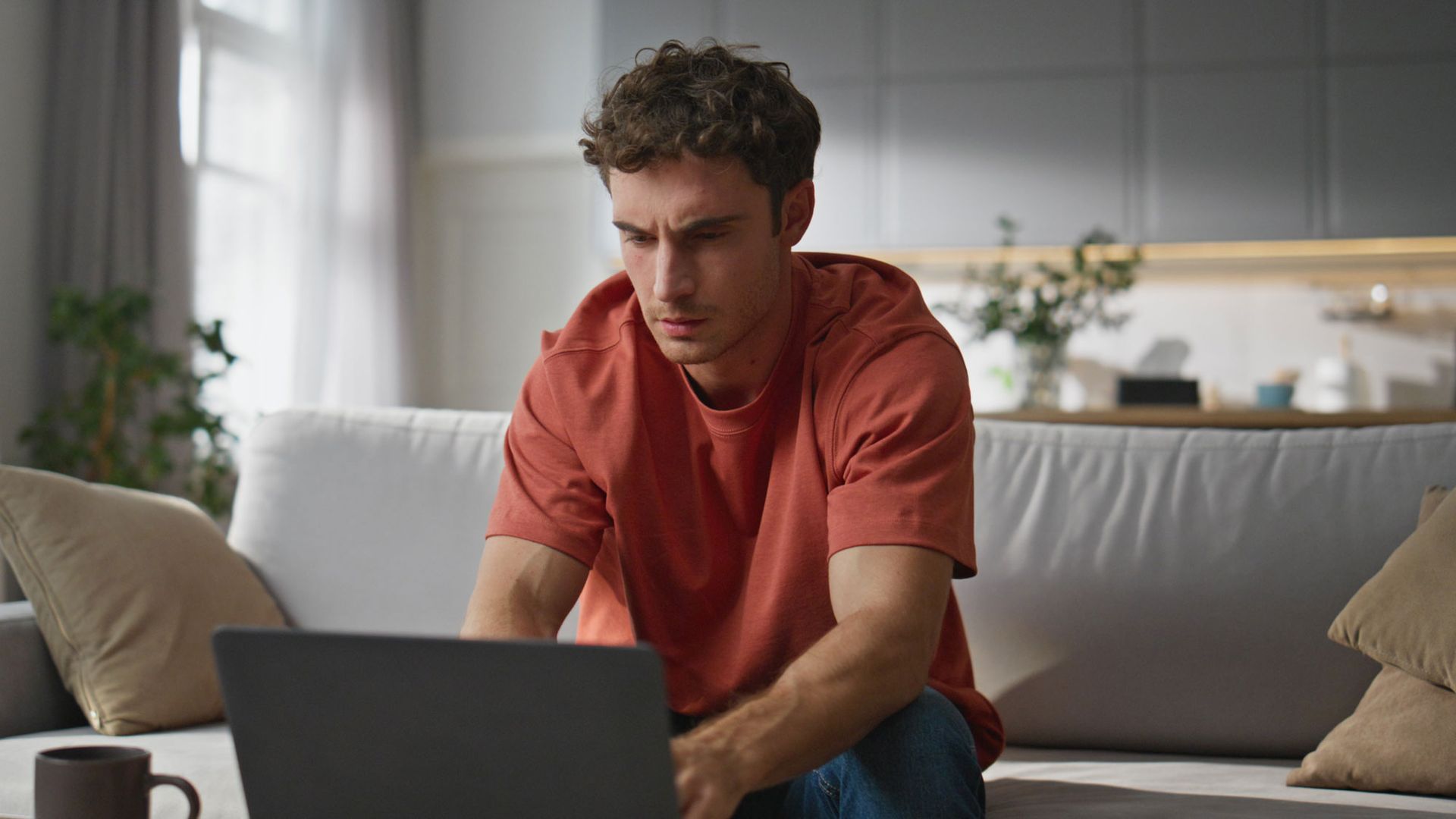 Serious looking man sitting in home on laptop