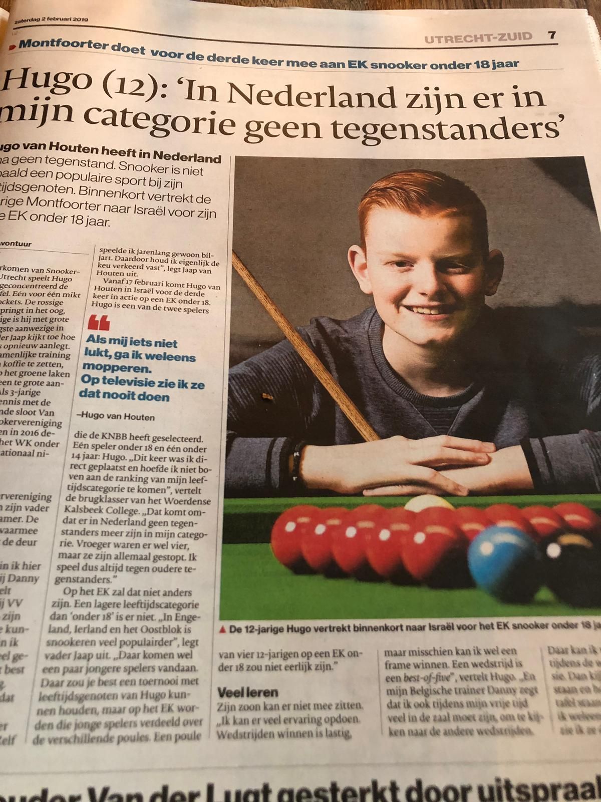Artikel over een jonge jongen, Hugo (12), die pool speelt. Hij glimlacht, poseert met een keu en staat voor de pooltafel.