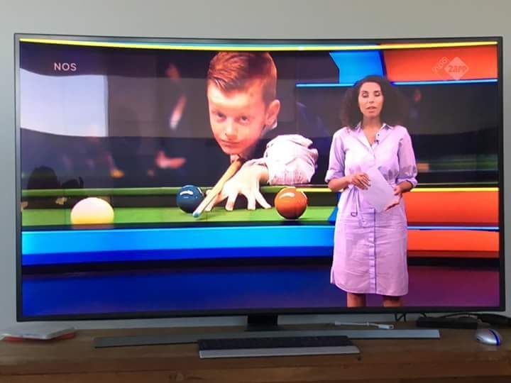 A TV screen shows a woman in a pink dress and a young boy playing snooker. The background is colorful.