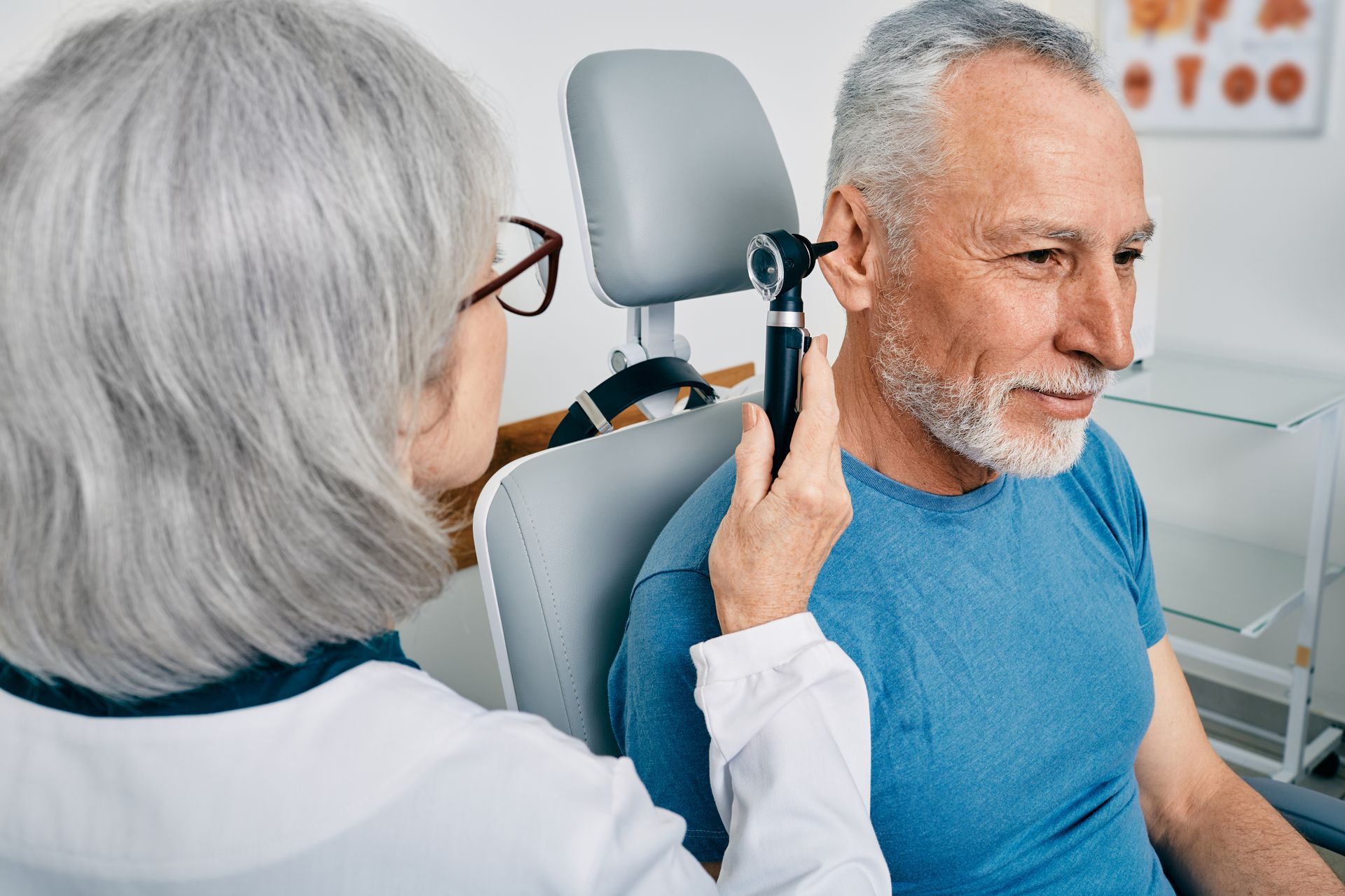 Doctor examining a patient's ear with an otoscope in a medical office.