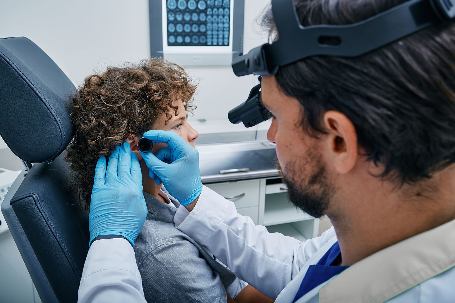 Doctor examining a patient's ear with medical tools in a clinic setting.