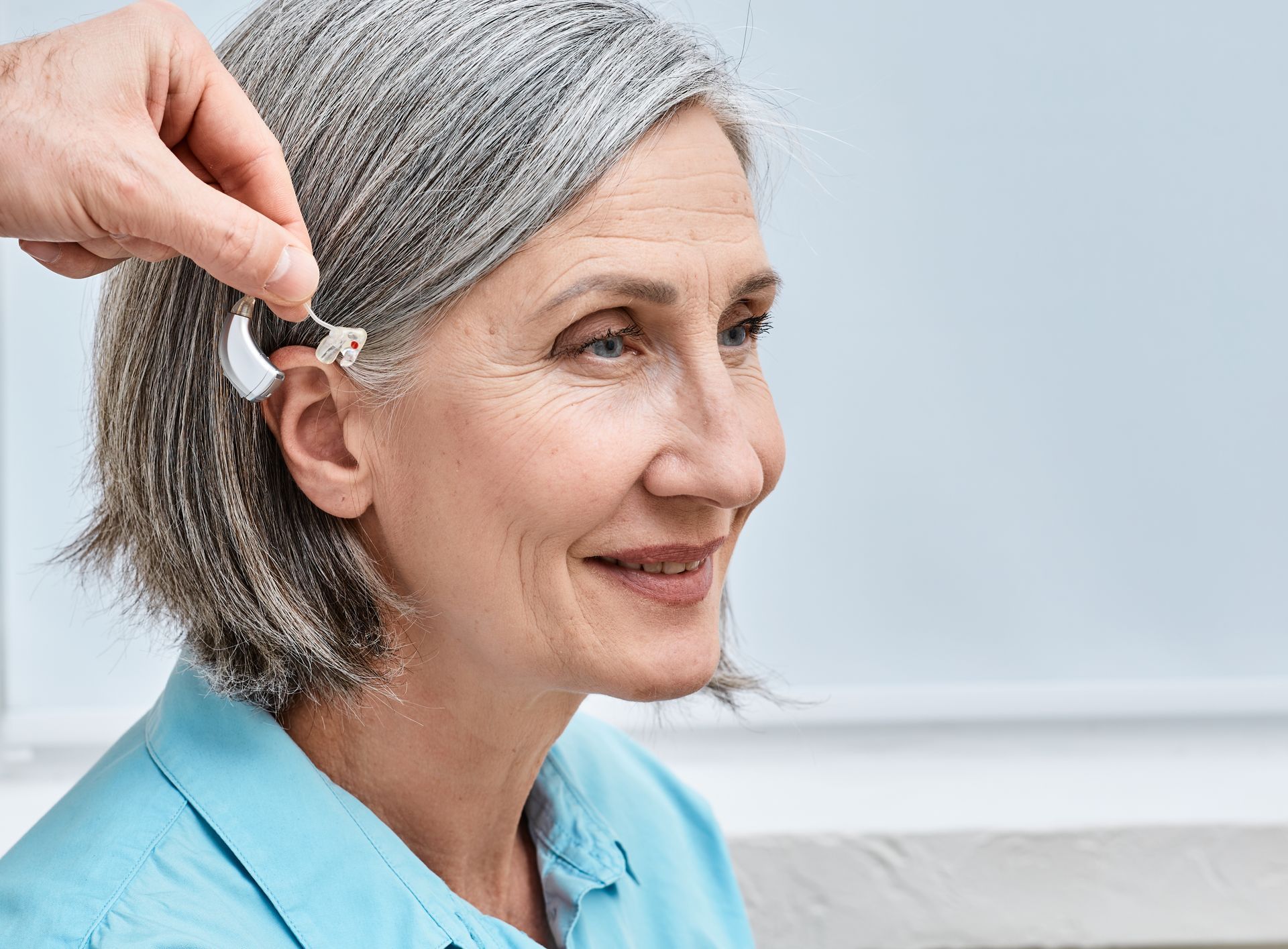 Person receiving a hearing aid fitting; indoor setting.