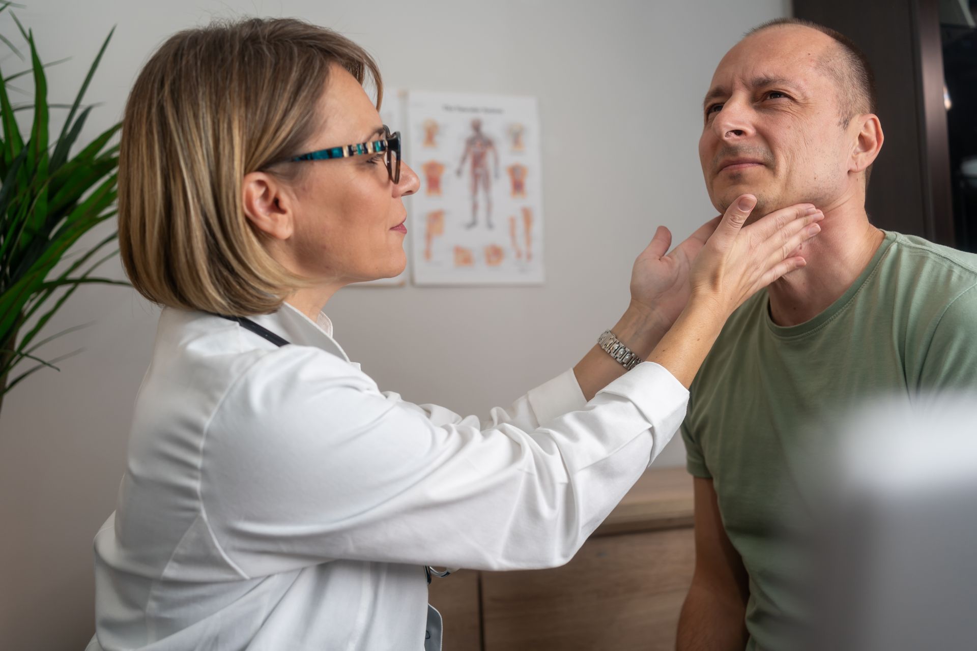 Doctor palpates a patient's neck during a medical exam in an office.