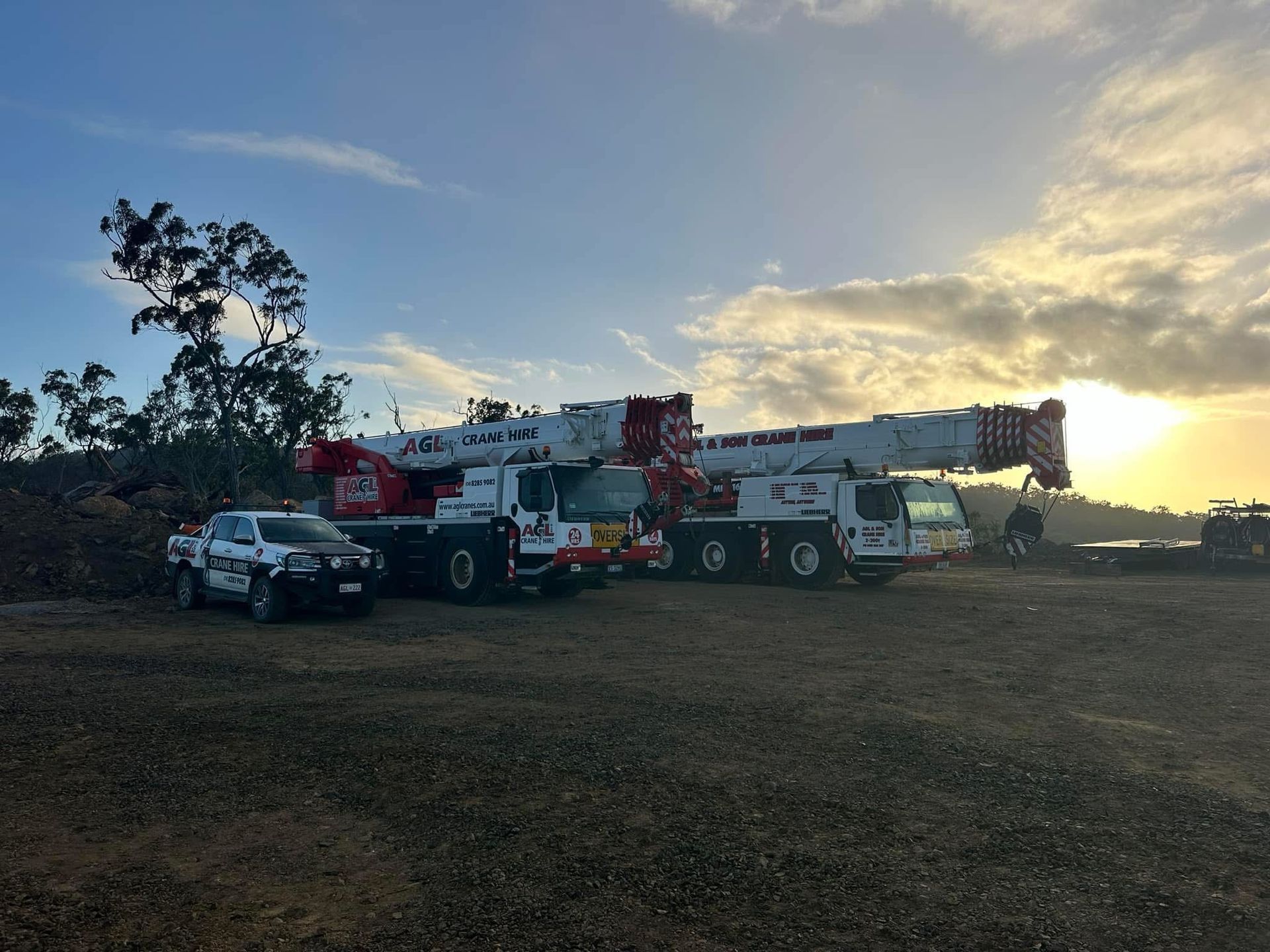 A row of trucks parked in a field with a sunset in the background | AGL & Son