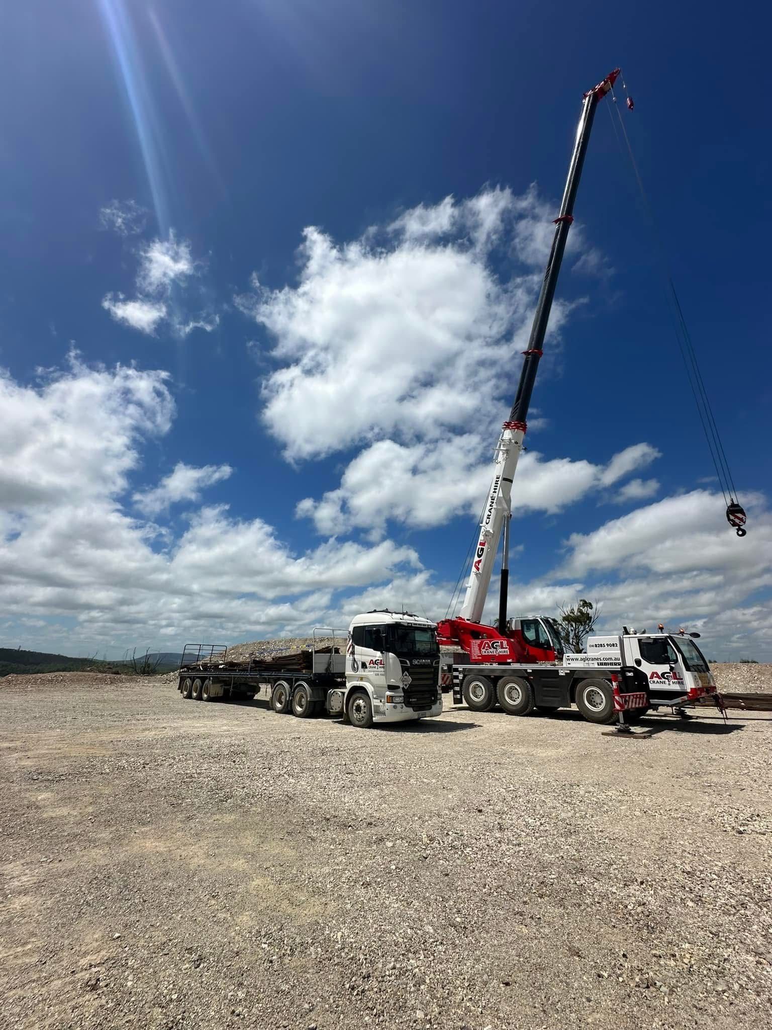 A large crane and a truck in a gravel lot | AGL & Son
