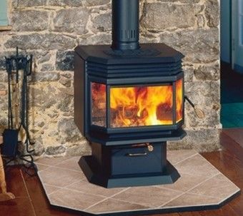 A wood stove is sitting in front of a stone wall