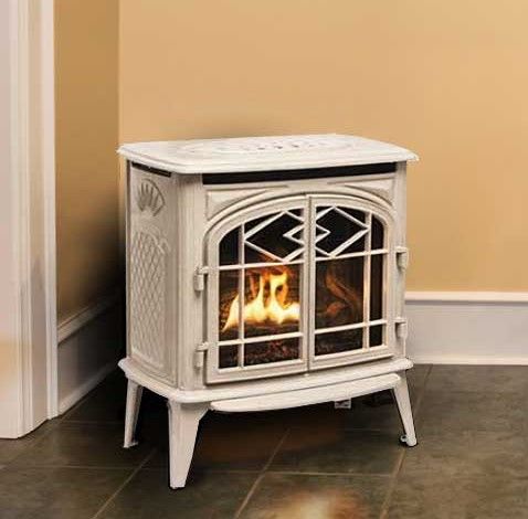 A white wood stove is sitting in a corner of a room.