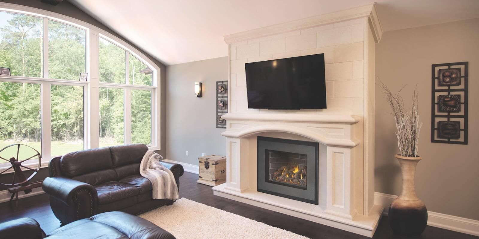 A living room with a fireplace , couch , television and large windows.