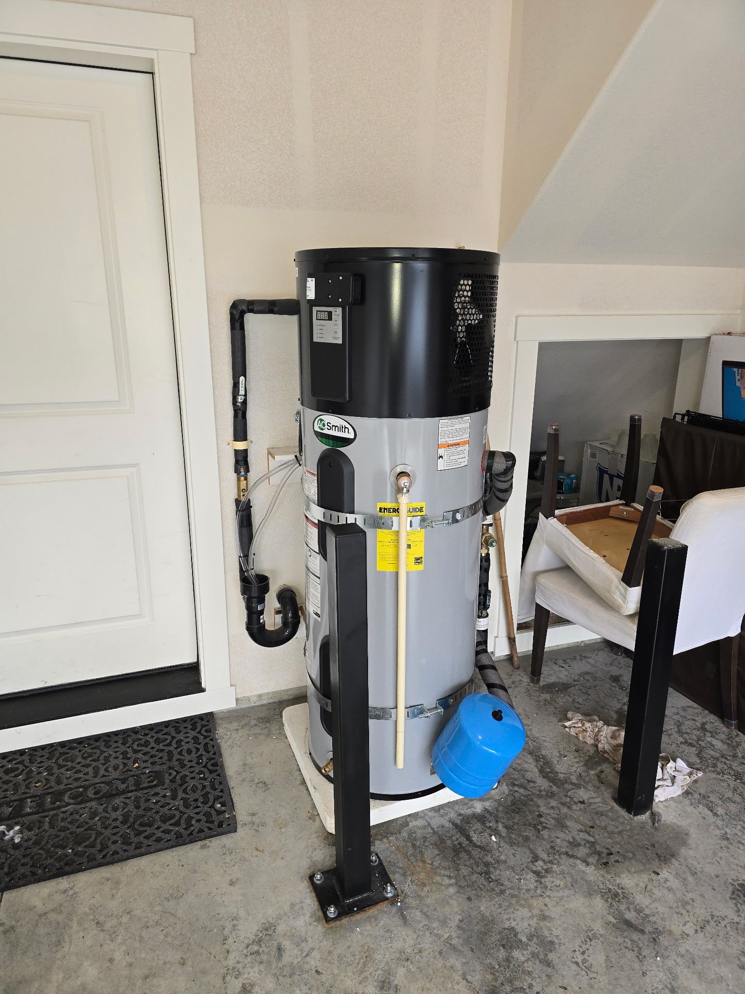Commercial air compressor in a garage beside a white door and workbench