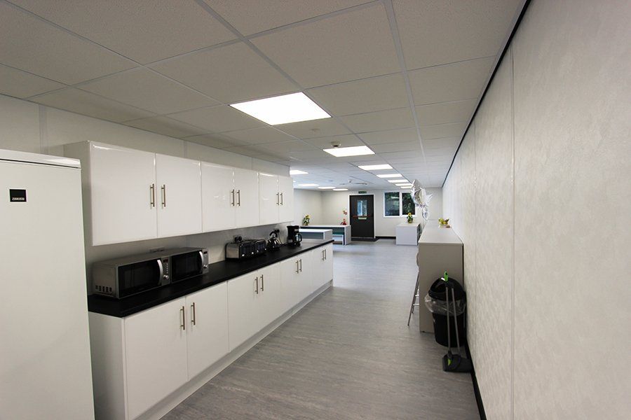 An area featuring white cabinets and black countertops, designed as a mobile office kitchen space