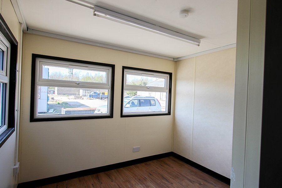 Interior of a Plastisol jackleg cabin featuring two windows and a wooden floor