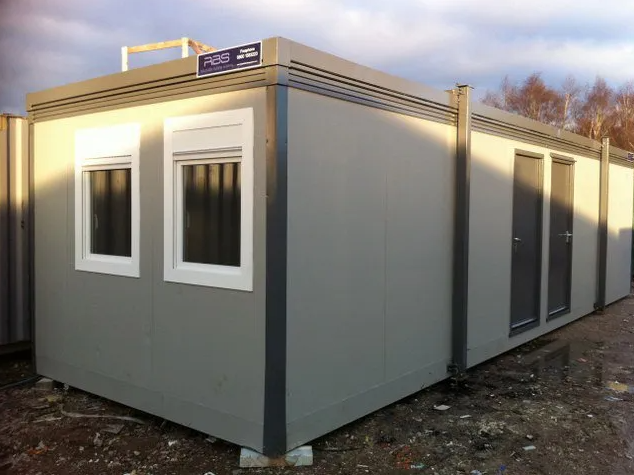 A grey jackleg cabin portable office building featuring multiple windows and doors