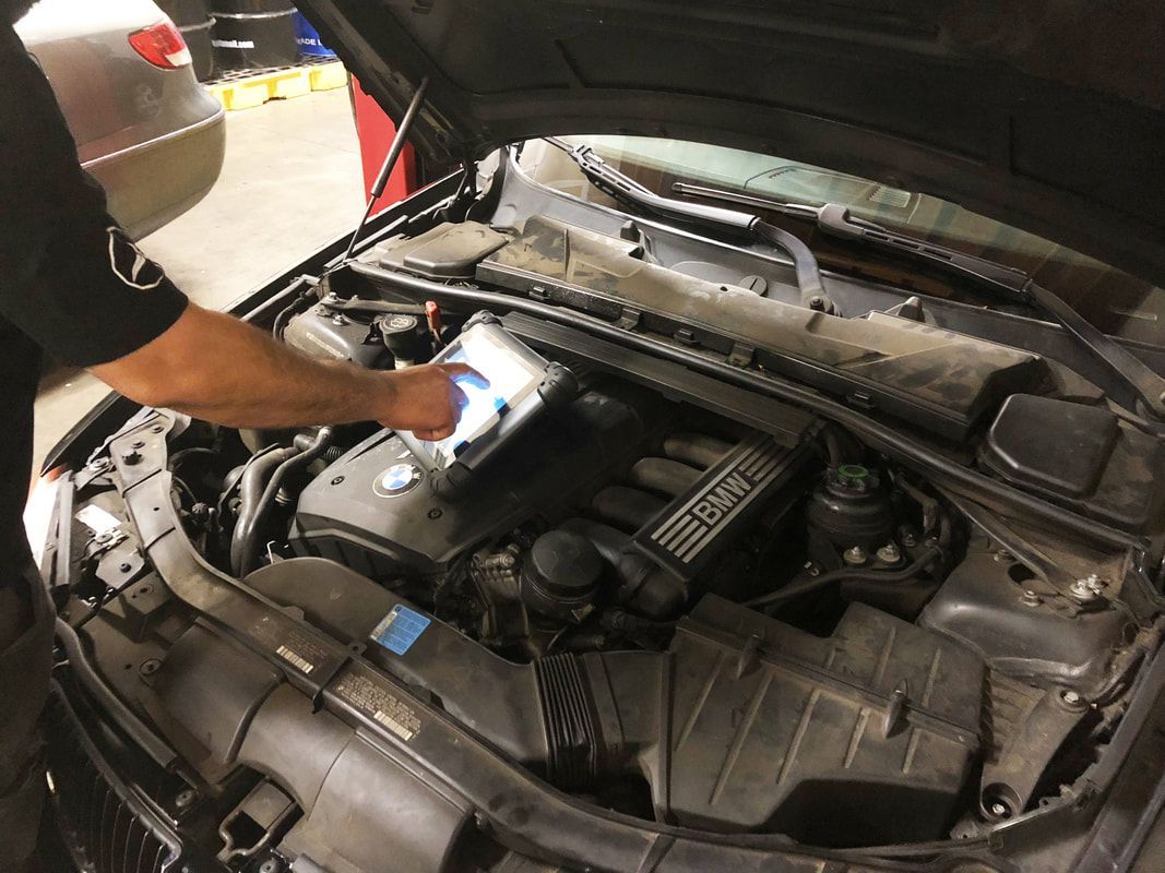 A man is looking under the hood of a car.