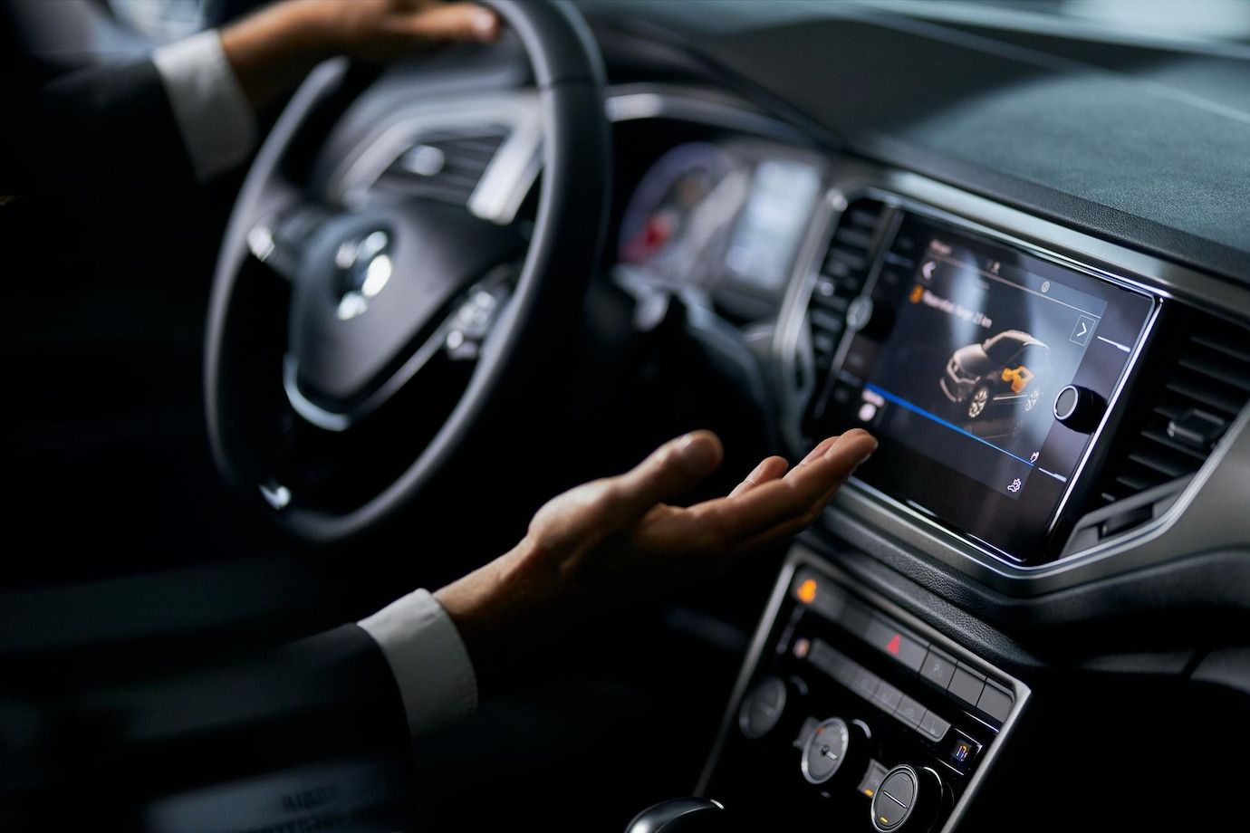 A man is driving a car and pressing a button on the dashboard.