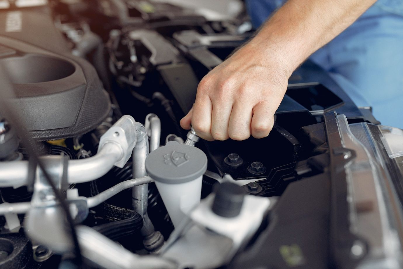 A man is working on the engine of a car.