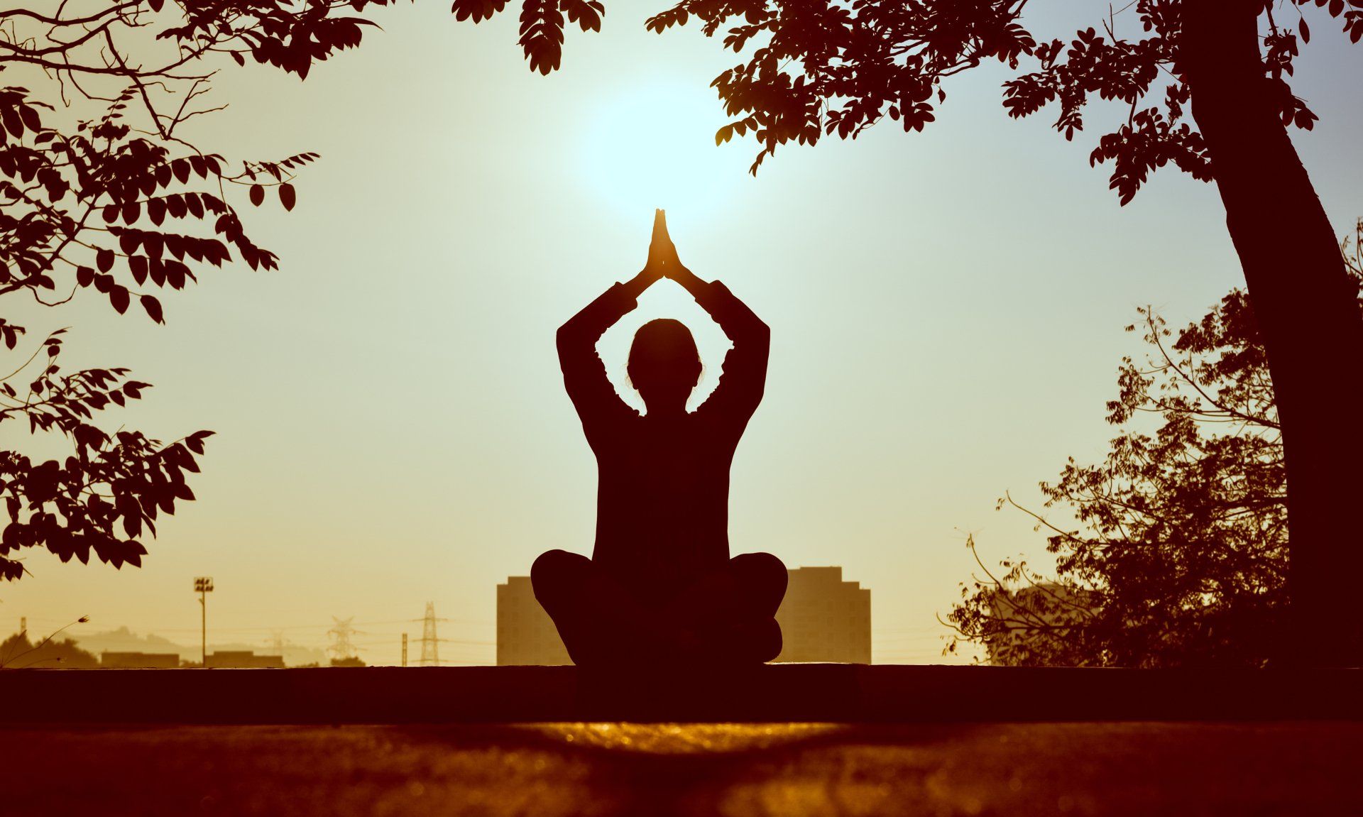 person meditating with the sun shining in the background