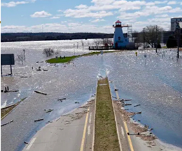 A flooded road with a lighthouse in the background